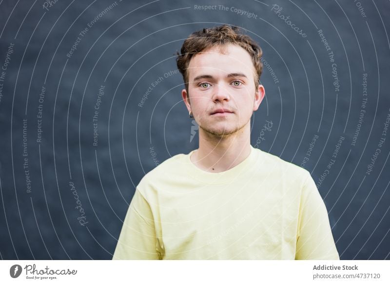 Young man looking at camera in studio appearance model short hair individuality style personality brown hair portrait male green eyes calm indifferent earring