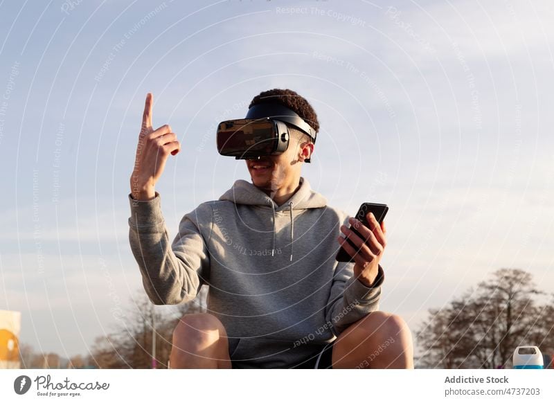 Man in VR headset with smartphone in city man vr cyberspace simulate explore street browsing futuristic index finger virtual reality digital male modern gadget