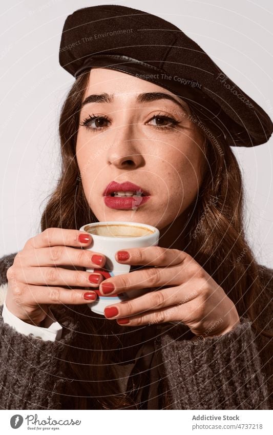 Stylish lady with cup of coffee in studio woman model hot drink beverage mug style portrait beret female warm leisure personality sweater pleasant enjoy trendy