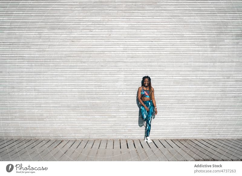 Happy black woman in sports outfit standing on wooden walkway positive healthy training wellbeing fitness happy activity activewear female individuality