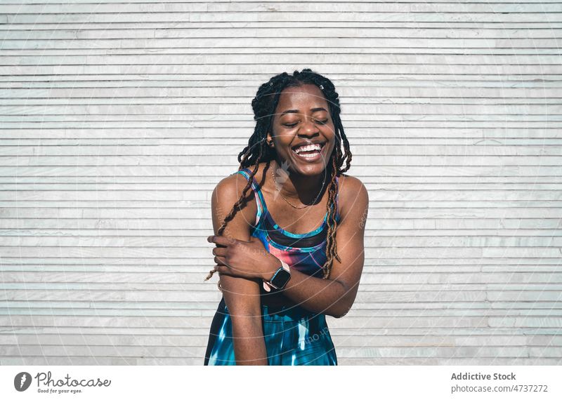 Cheerful black woman in sportswear standing on boardwalk after training laugh happy fitness joy wellness healthy lifestyle practice female walkway legs crossed