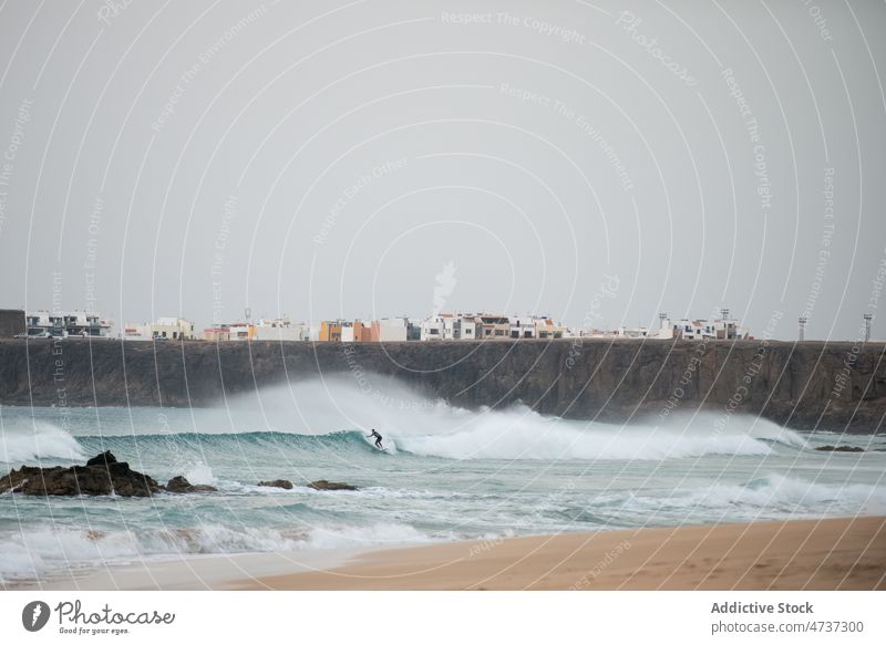 Surfer riding surfboard on foamy sea waves in cloudy day surfer stormy extreme activity ocean practice danger shore person splash sport power beach coast water