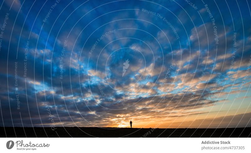 Lonely person in vast valley under cloudy sundown sky silhouette sunset freedom scenery lonely countryside harmony scenic nature rural spacious endless