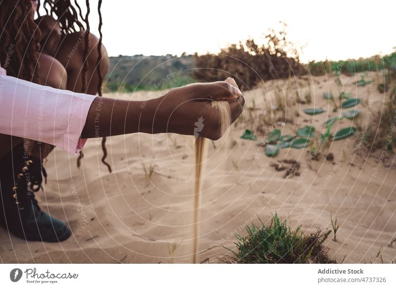 Crop black woman with handful of sand on seashore spill beach summer sunset evening pour female ethnic african american nature coast harmony idyllic twilight