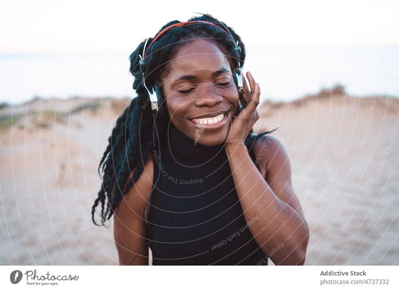 Carefree black woman listening to music on beach dance song headphones summer seashore having fun female ethnic african american carefree freedom enjoy cheerful