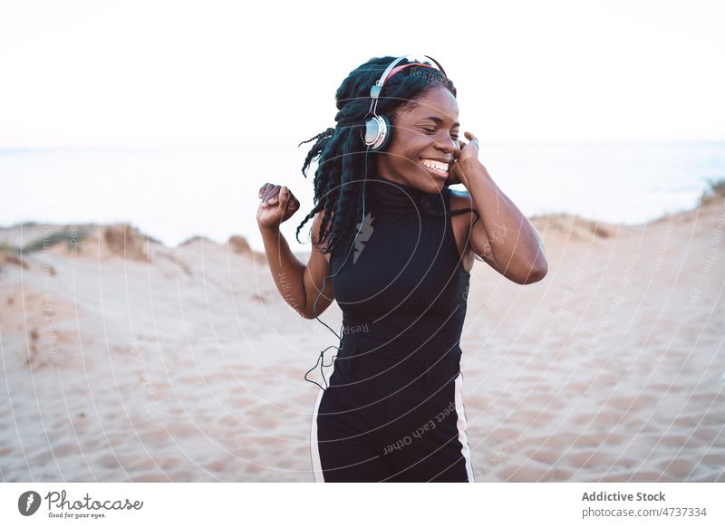 Carefree black woman listening to music on beach dance song headphones summer seashore having fun female ethnic african american carefree freedom enjoy cheerful