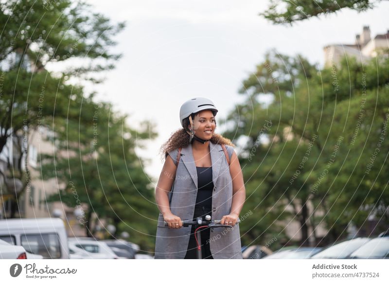 Smiling black woman riding electric scooter on asphalt road ride alternative commute transport eco eco friendly convenient formal female city vehicle street