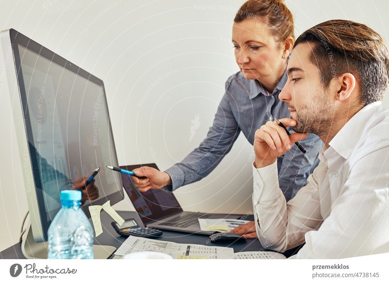 Business colleagues discussing financial data working together in office. People entrepreneurs working with charts and tables on computer. Two people working together