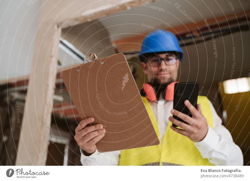 foreman or architect working on mobile phone blueprints .construction site. Home improvement technology internet house professional insulating ear defenders