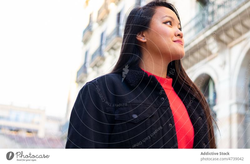 Smiling Asian woman standing on street during old buildings admire carefree observe appearance positive city explore personality portrait female smile long hair