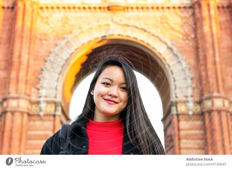 Smiling Asian woman standing on street during old buildings admire carefree observe appearance positive city explore personality portrait female smile long hair