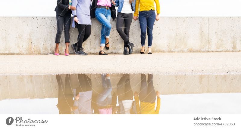 Group of faceless women on embankment friendship street city bonding pastime spend time group arms raised waterfront urban relationship together reflection