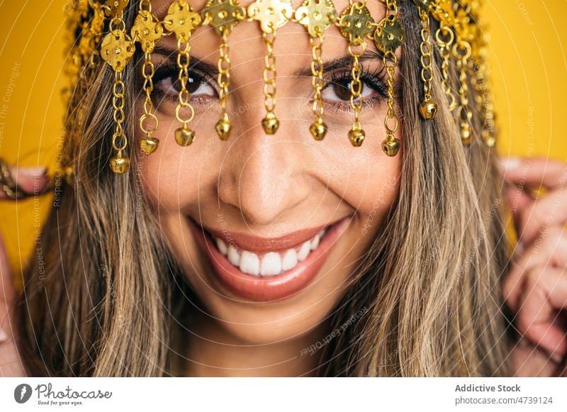 Charming woman wearing tassel headband in studio portrait style individuality cool cheerful makeup chain female editorial model optimist positive smile