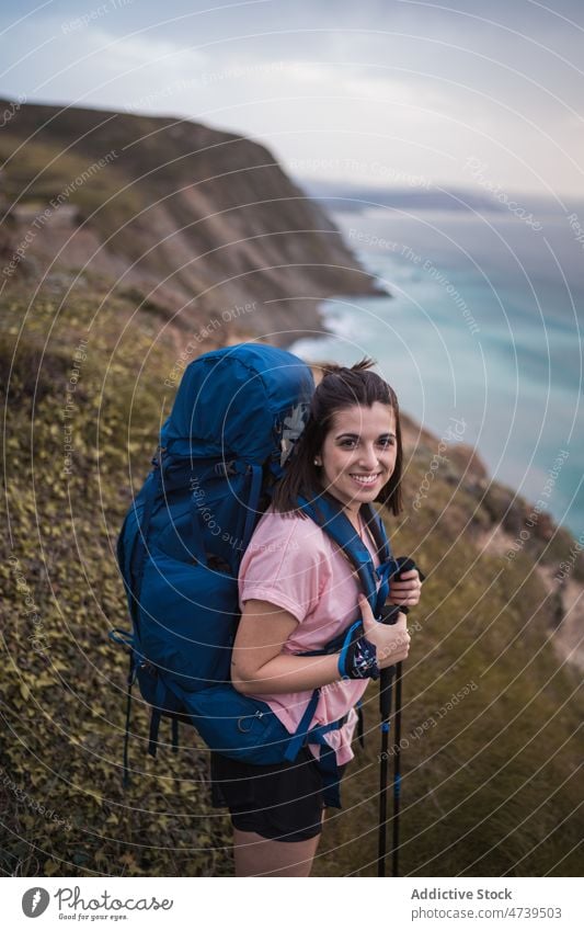 Cheerful hiker on shore at sunset time woman trekking adventure nature sea seashore waterfront pole sundown evening stick waterside happy seaside seafront