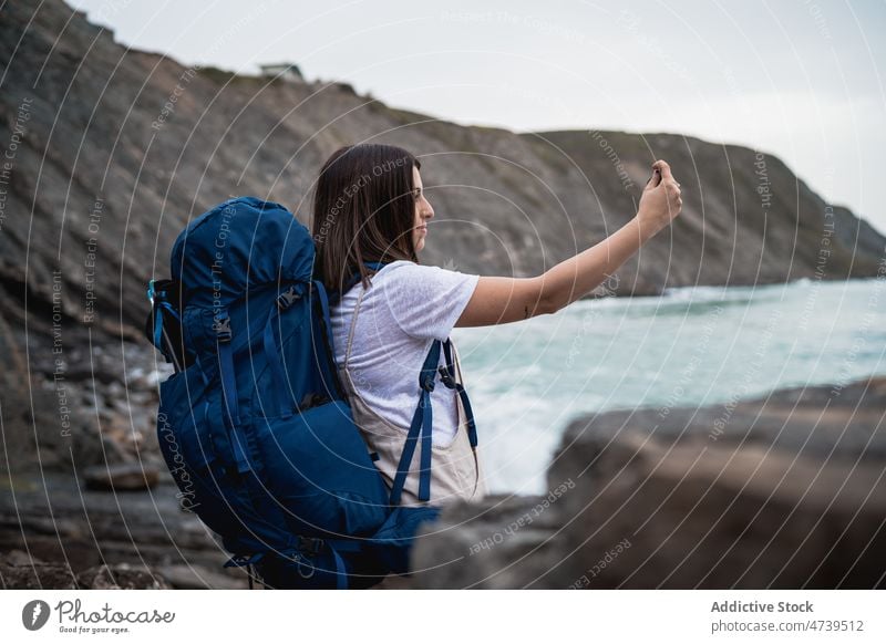 Female hiker taking photo of sea woman trekking water selfie photography adventure self portrait take photo social media smartphone waterfront journey seashore