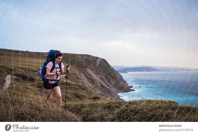 Cheerful hiker on shore at sunset time woman walk trekking adventure nature sea seashore waterfront pole sundown evening stick waterside happy seaside seafront