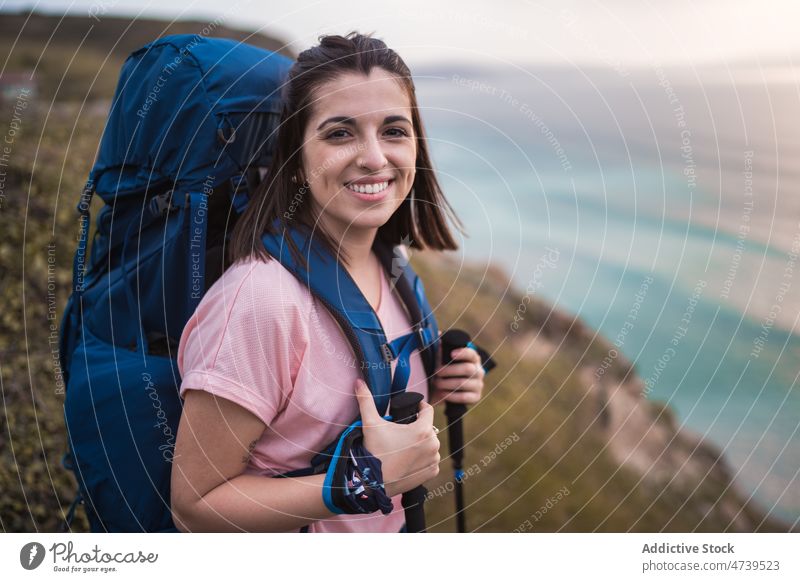 Cheerful hiker on shore at sunset time woman trekking adventure nature sea seashore waterfront pole sundown evening stick waterside happy seaside seafront