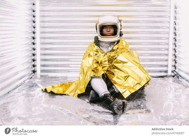 Black astronaut wrapped in emergence blanket woman spacesuit helmet spaceship cosmonaut emergency thermal safety costume mission survival uniform modern