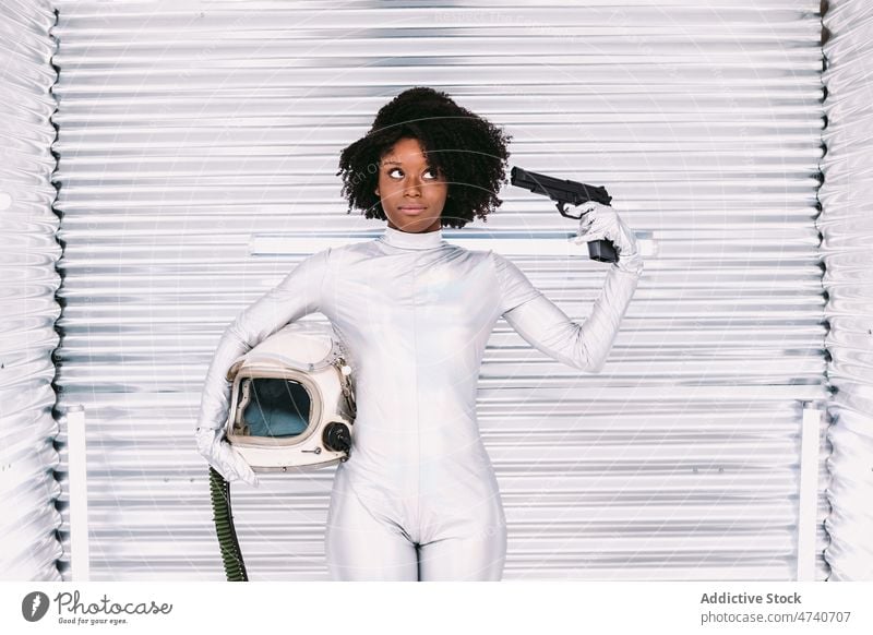 Black astronaut pointing gun at head woman spacesuit spaceship cosmonaut costume mission weapon dangerous uniform modern safety african american black light