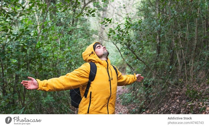 Man in wool cap standing in forest man hiker nature trekking tree journey eyes closed extended arms explore trip woods activity adventure beard male explorer