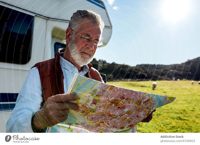 Senior man with map near trailer motorhome car rv camper nature road trip senior navigate check mature journey caravan field countryside transport parked male