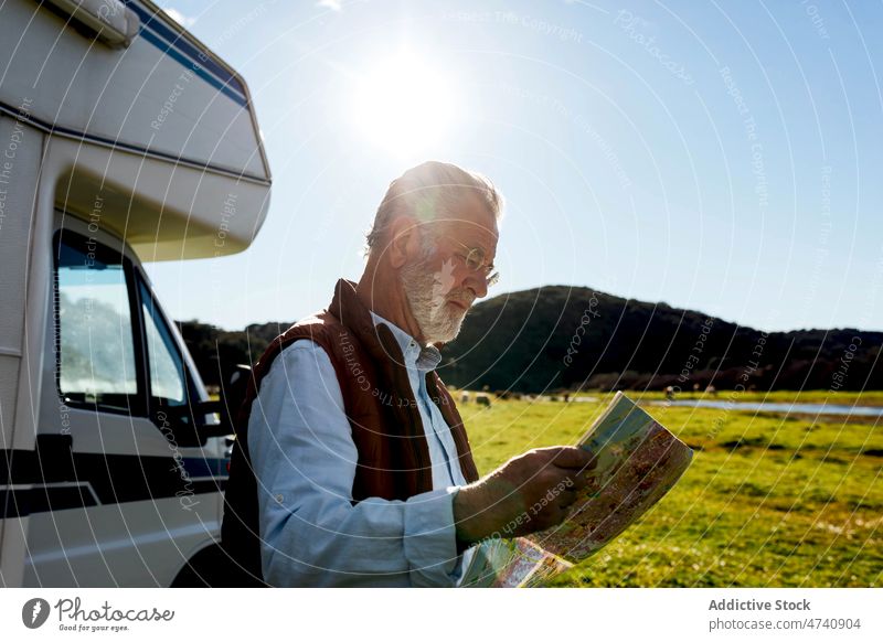 Senior man with map near trailer motorhome car rv camper nature road trip senior navigate check mature journey caravan field countryside transport parked male