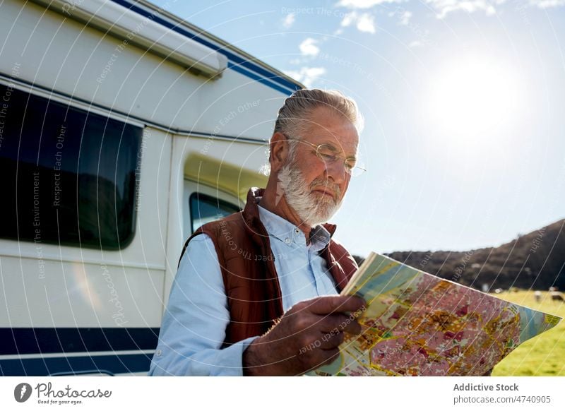 Senior man with map near trailer motorhome car rv camper nature road trip senior navigate check mature journey caravan field countryside transport parked male