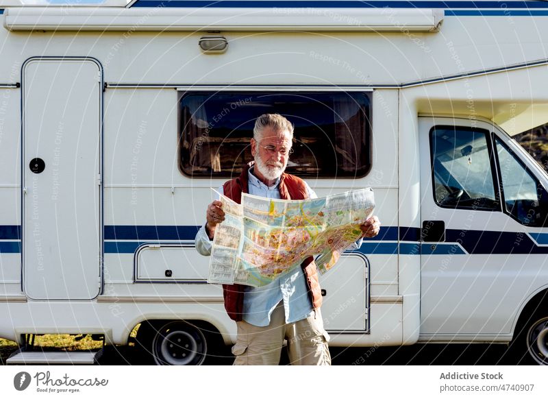 Senior man with map near trailer motorhome car rv camper nature road trip senior navigate check mature journey caravan field countryside transport parked male