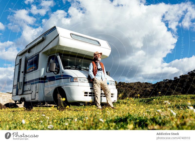 Senior man near camper in nature motorhome car rv field road trip senior journey traveler caravan trailer countryside transport parked male auto photo camera