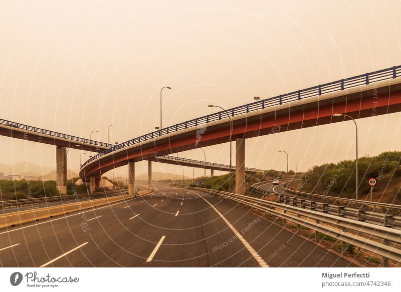 Highway with bridges at various levels on a day with Saharan dust in the environment, creating a foggy atmosphere. highway saharan dust haze road travel viaduct