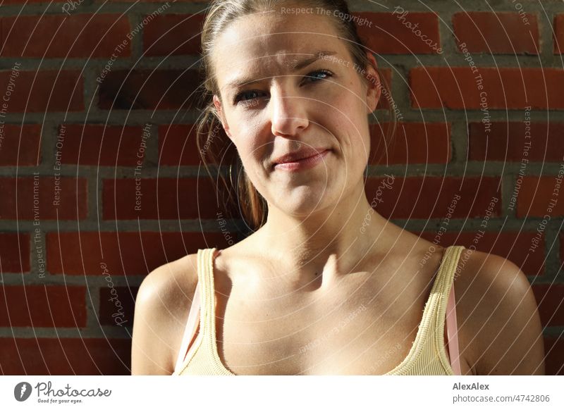 Portrait of young tall blonde woman with dimples smiling at camera Tank top kind fortunate Looking into the camera Central perspective pit Close-up Youthfulness