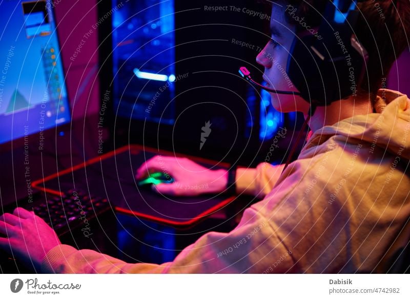 Boy plays computer game at home, gaming addiction gamer workplace boy keyboard virtual entertainment online cybersport equipment streamer male man technology