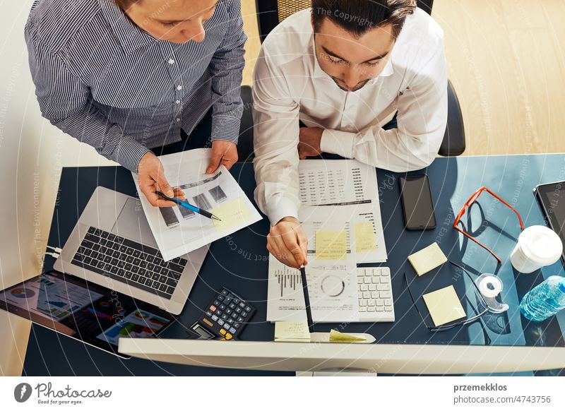 Business colleagues discussing financial data working together in office. People entrepreneurs working with charts and tables on computer. Two people working together