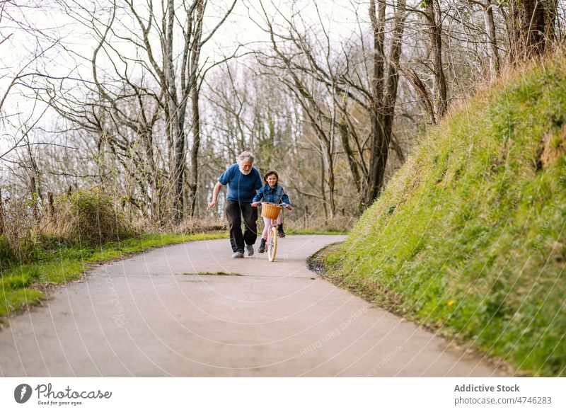 Grandfather teaching girl riding bicycle in countryside grandfather hobby leisure childhood spend time ride help spare time man care learn activity kid