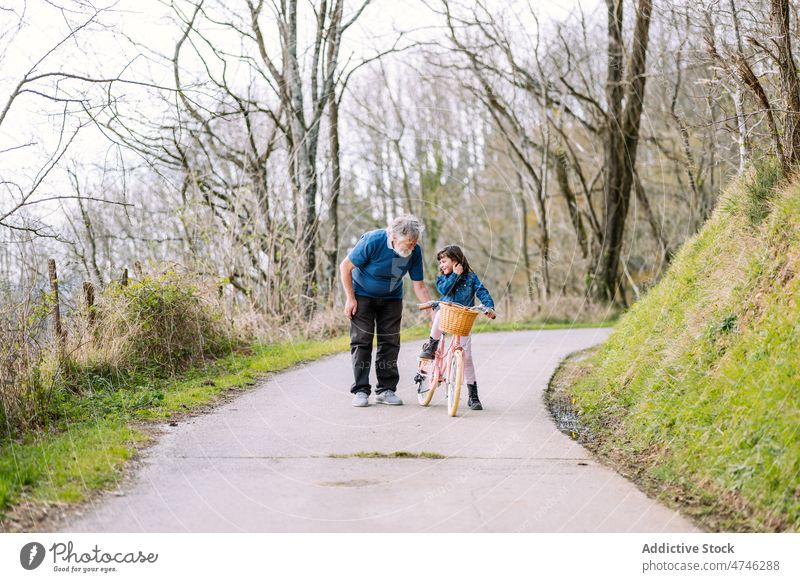 Grandfather teaching girl riding bicycle in countryside grandfather hobby leisure childhood spend time ride help spare time man care learn activity kid