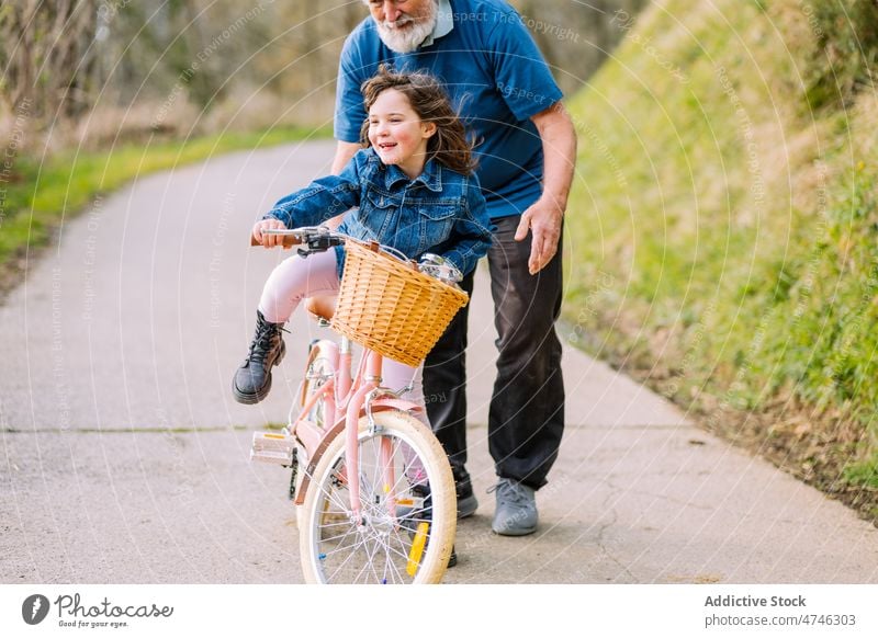 Grandfather teaching girl riding bicycle in countryside grandfather hobby leisure childhood spend time ride help spare time man care learn activity kid