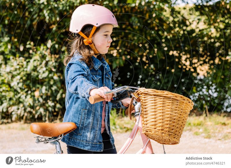 Girl walking with bicycle in park girl kid hobby leisure pastime childhood recreation transport helmet path basket activity summer bike tree safety summertime