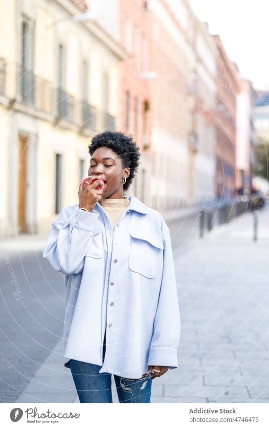 Black woman eating apple on street fruit healthy food city vitamin walkway style appearance feminine urban black african american female summer casual lady