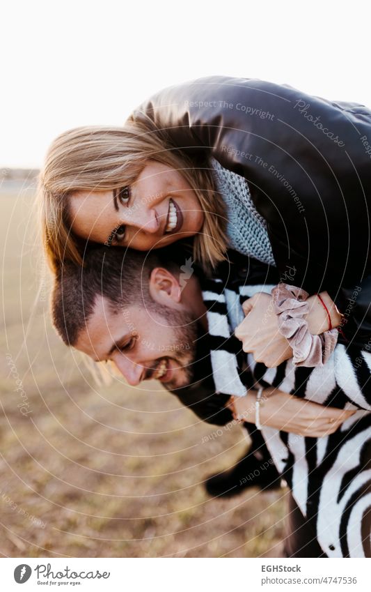 Close up couple piggyback in the countryside embraced. Boyfriend and girlfriend in love embracing journey weekend people man woman adult nature outdoors