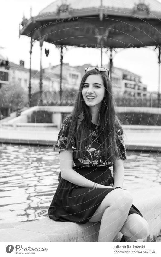 Young woman with long hair sitting at fountain Sit Uniqueness Hip & trendy Friendliness Authentic T-shirt Model pretty Girl Dream Long-haired Lifestyle Woman