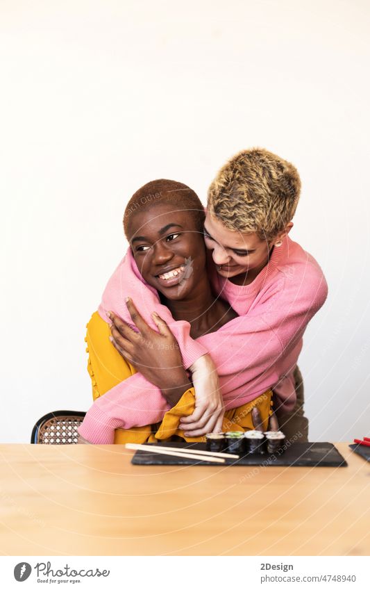 Two happy affectionate young woman hugging each other in a close embrace while laughing and smiling, young multiracial female friends two together embracing