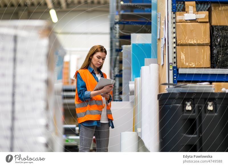 Woman with tablet in factory storehouse checking location of goods business cargo confident delivering delivery distribution employee female industrial industry