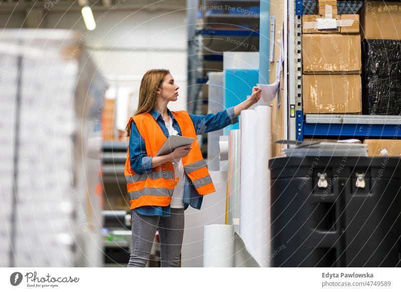 Woman with tablet in factory storehouse checking location of goods business cargo confident delivering delivery distribution employee female industrial industry