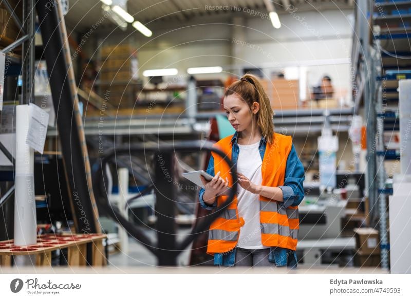 Woman with tablet in factory storehouse checking location of goods business cargo confident delivering delivery distribution employee female industrial industry