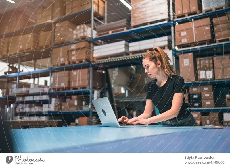 Woman using laptop at warehouse business cargo confident delivering delivery distribution employee factory female goods industrial industry job logistics