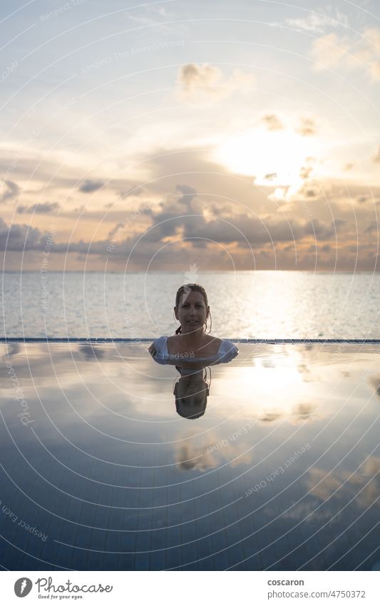 Woman into a infinity swimming pool near the ocean attractive beach beautiful bikini blue dusk enjoying female fun girl happiness health holiday hotel island