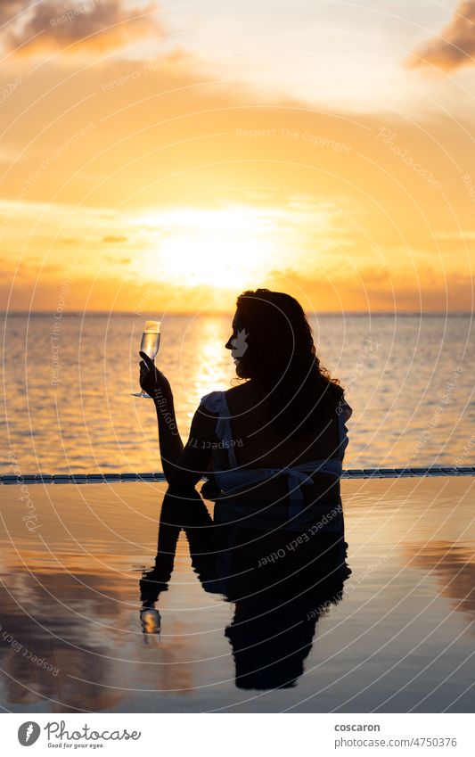 Attractive woman on a infinity pool near the ocean with a glass of champagne.Back view alone back beautiful beauty cocktail enjoying evening female happiness