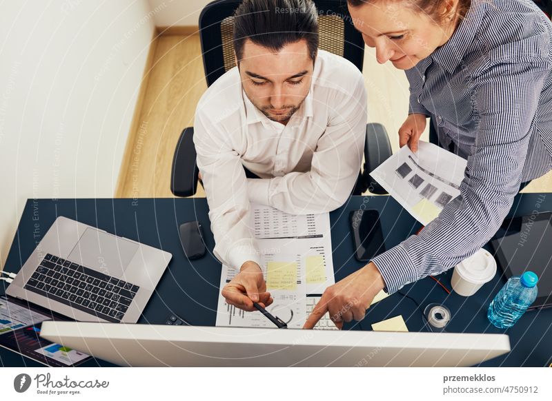 Business colleagues discussing financial data working together in office. People entrepreneurs working with charts and tables on computer. Two people working together