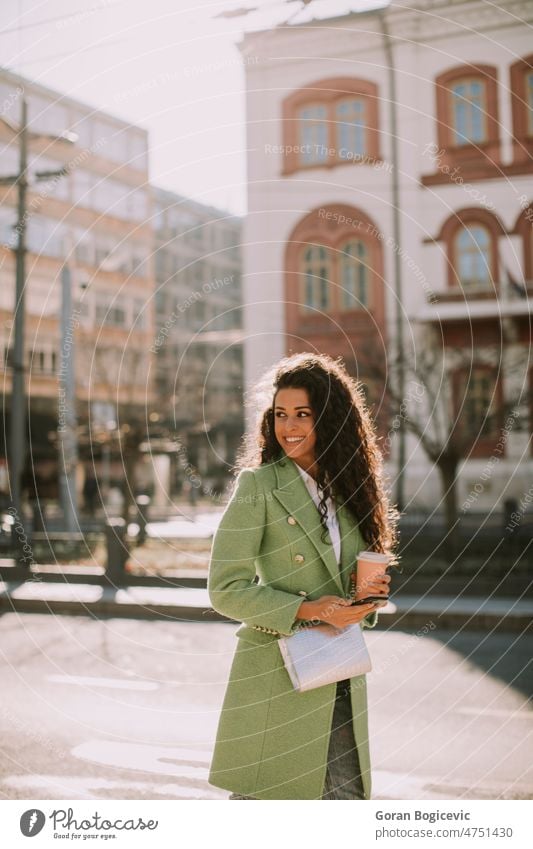 Young woman using smartphone on the street and holding takeaway coffee beautiful people beautiful woman casual cellphone cheerful city city life city street