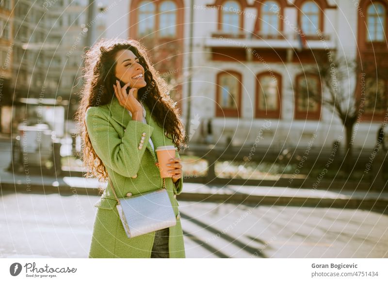 Young woman using smartphone on the street and holding takeaway coffee beautiful people beautiful woman casual cellphone cheerful city city life city street